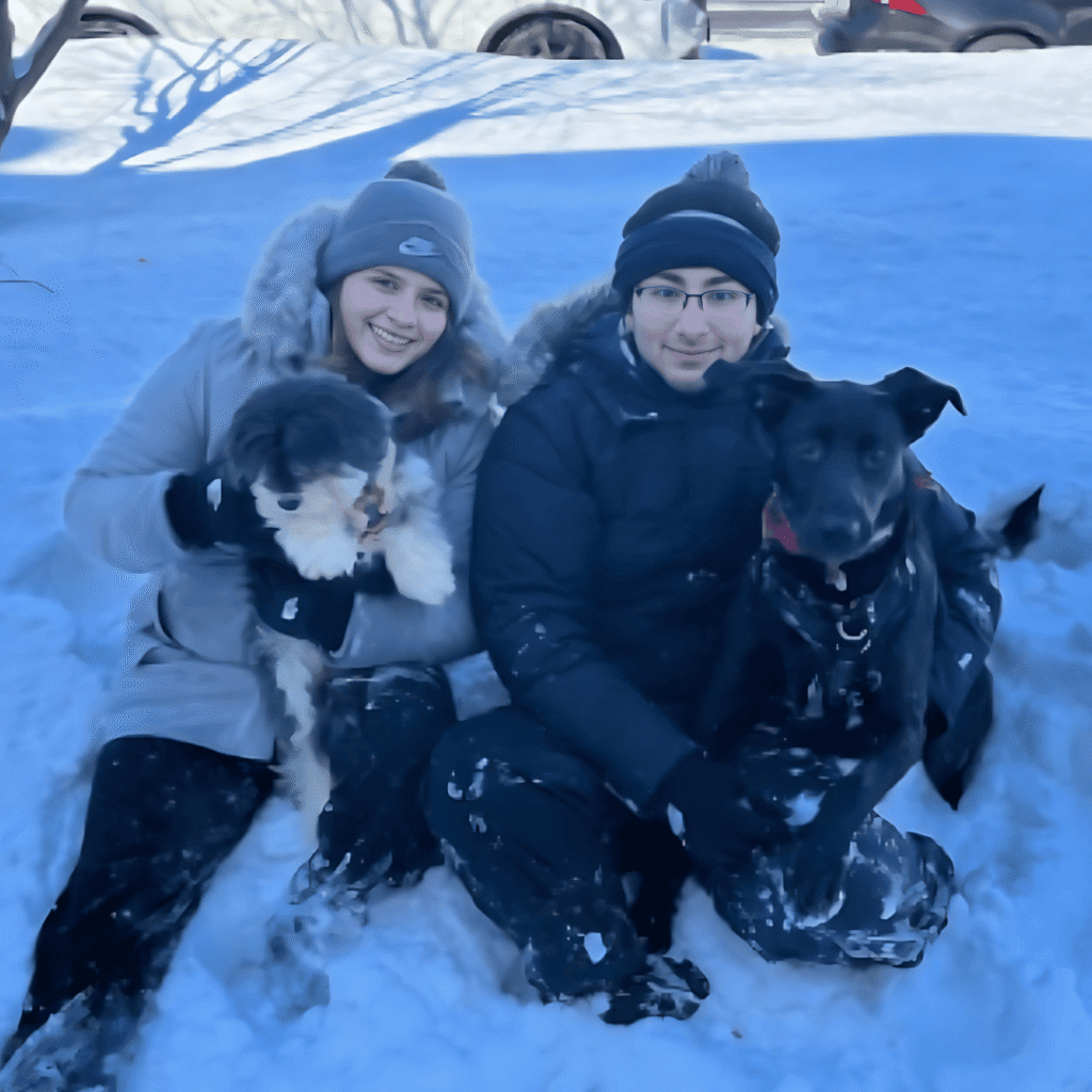 Isabella y su prometido en la nieve con sus dos perros. 
